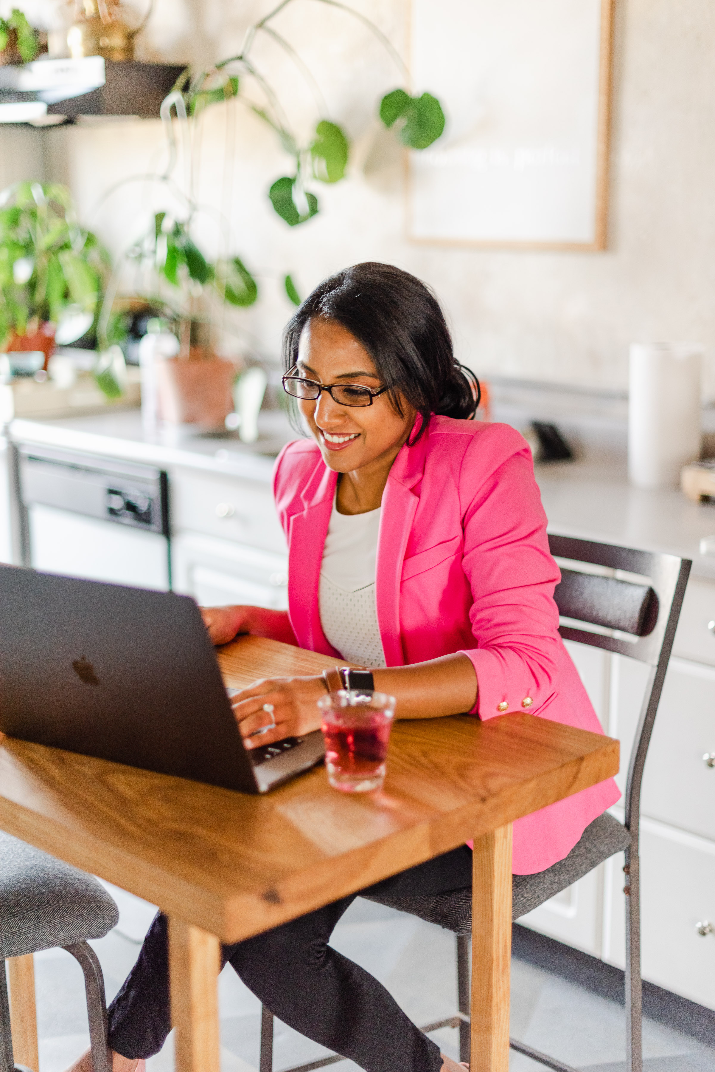Divya working at her kitchen table in a pink blazer